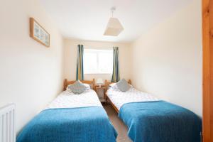 two beds in a small room with a window at Buckingham Cottage - Lancombes House in Powerstock