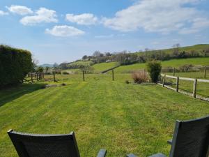 a grassy yard with two chairs and a fence at Buckingham Cottage - Lancombes House in Powerstock