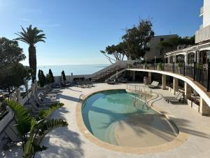 Una piscina junto a la playa con sillas y el océano. en Ilunion Caleta Park, en Sant Feliu de Guíxols