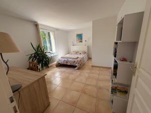 sala de estar con cama y suelo de baldosa en Logement avec jardin et terrain de pétanque privé, en Venelles