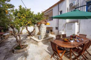 a wooden table with chairs and an umbrella on a patio at Ambra - Luxury & Big Apartment with Garden & Pool in Casamassella