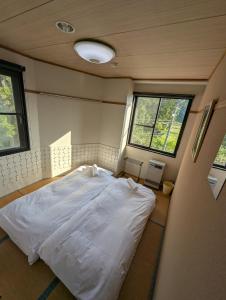 a bedroom with a white bed in a room with windows at Gondola House in Nozawa Onsen