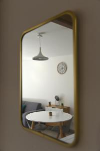 ein Spiegel, der ein Zimmer mit einem Tisch und einer Uhr reflektiert in der Unterkunft Citadella Calvi confort chaleureux et climatisé in Calvi