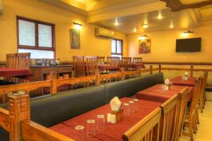 a restaurant with tables and chairs and a television at Hotel Lonavla in Lonavala
