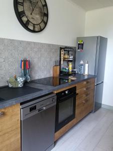 a kitchen with a large clock on the wall at appartement cosy parking privé in Chazey-sur-Ain