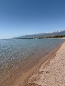 a beach with water and mountains in the background at Vzmorie apart #1 in Bosteri