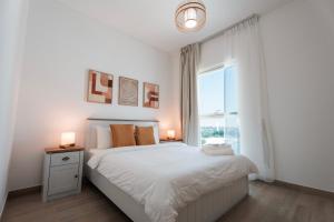 a white bedroom with a bed and a window at Yas Island 3BR plus Maid Pool, Gym, Near SeaWorld & Ferrari World in Abu Dhabi +22 photos