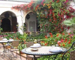 una mesa y sillas en un jardín con flores en Le Riad Meknes, en Meknès