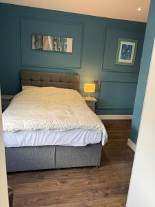 a bedroom with a bed and a blue wall at Turquoise Garden in Macclesfield +6 photos