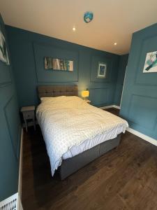 a bedroom with a large bed with blue walls at Turquoise Garden in Macclesfield