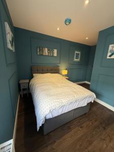 a bedroom with a large bed with blue walls at Turquoise Garden in Macclesfield