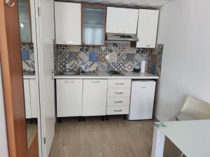 a small kitchen with white cabinets and appliances at Tramontana apartments in Dugobabe