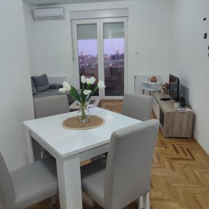 uma mesa de jantar branca com um vaso de flores em Apartman N&L em Sombor