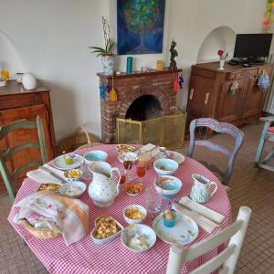 a table with plates of food on it with a fireplace at Chambres d'Hôtes Couleurs d'Elvine in Coutances +14 photos