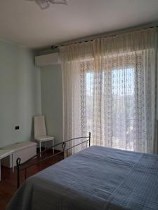 Un dormitorio con una cama y una ventana grande. en Roses house, en Porto San Giorgio