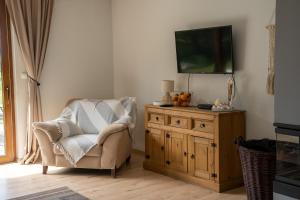 sala de estar con silla y tocador con TV en Kiton House, en Skarlin