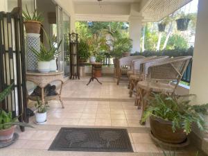 une terrasse couverte avec des chaises, des tables et des plantes en pot dans l'établissement Chambre cosy avec jardin à Pattaya, à Jomtien Beach