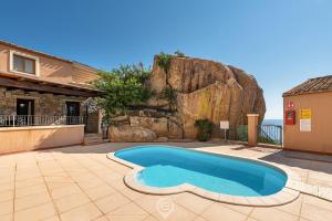a house with a swimming pool in front of a rock at Cliffside Blue in Costa Rei