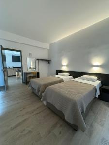 two beds in a hotel room with a tv at Sunflower Hotel Apartments in Larnaka