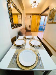 a dining room table with plates and glasses on it at 8 Skyline Sunset Suite in Iloilo City