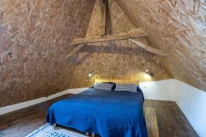 a bedroom with a blue bed in a attic at Maison De Vacances Chêne in Auriac-du-Périgord