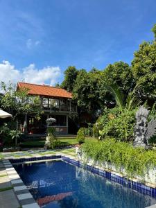 a swimming pool in front of a house at Villa Rumah Kayu Lovina in Lovina
