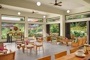 a living room with tables and chairs and windows at Gateway Coorg in Madikeri