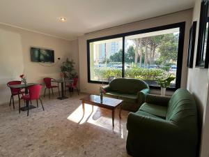 a living room with a couch and tables and a large window at Hotel Ines in Cesenatico