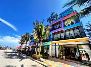 Un edificio con palmeras frente a una calle. en Flamingo Ibiza Hải Tiến Luxury Resort, en Thanh Hóa