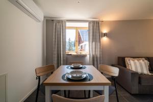 un soggiorno con tavolo, sedie e divano di Lussari Style Apartments a Tarvisio