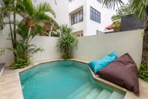 een zwembad in de achtertuin met een bank en palmbomen bij Sofia Villa by betterplace in Canggu