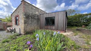 a brick and wooden house with flowers in the yard at The Piggery near Bruton in Evercreech