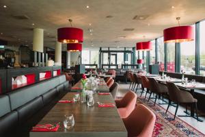 a restaurant with tables and chairs and red chandeliers at Bastion Hotel Breda in Breda