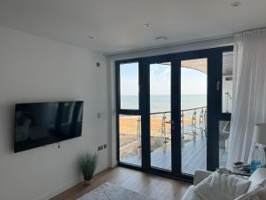 a living room with a flat screen tv and a balcony at Apartment in Kent Beachfront NEW in Ramsgate
