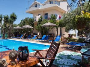 a swimming pool with a table and chairs next to a house at Tsimogiannis Dynamiki Sea View Apartments in Kanali