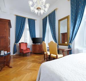 a bedroom with a bed and two chairs and a mirror at Charles Bridge Palace in Prague