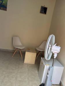 a room with two chairs and a white fan at Serene Room and Living Room in Serekunda