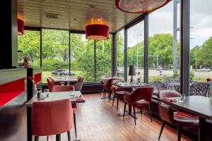 a restaurant with tables and chairs and large windows at Bastion Hotel Amsterdam Noord in Amsterdam