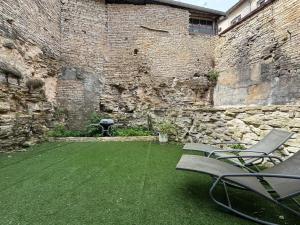 a courtyard with two chairs and a stone wall at La Bella Vigna - Essoyes - 6 prs - 3 bdr in Essoyes