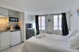 Un dormitorio con una cama blanca y una cocina. en Le Petit Pithou - studio équipé simple et plein coeur de la ville 2, en Troyes 25 fotos más