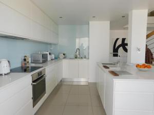 a white kitchen with white cabinets and appliances at Penthouse Strand in Strand