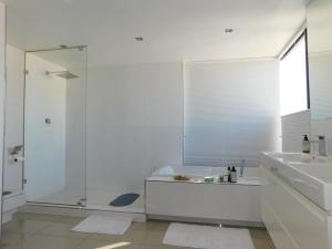 a white bathroom with a shower and a sink at Penthouse Strand in Strand +27 photos