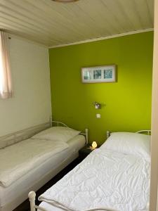 due letti in una stanza con una parete verde di Haus Merle a Tossenserdeich Altre 5 foto