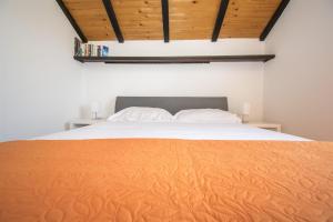 a bedroom with a large bed with an orange blanket at Apartments Njoko in Prvić Šepurine