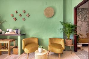 a green room with two chairs and a table at Bed and Breakfast La Ruta Naranja in Adsubia