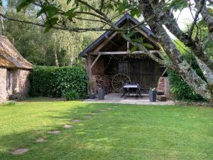 une grange avec une table et une roue dans une cour dans l'établissement Chambres d'Hotes - La Marmoire, à Soudan