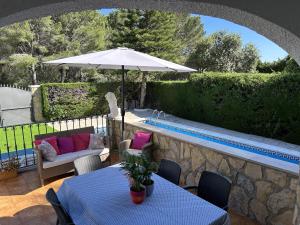 a patio with tables and an umbrella and a pool at Pino Alto Villa Jazmin in Miami Platja