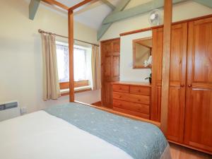 a bedroom with a bed and a dresser and a mirror at Barn Cottage in Liskeard