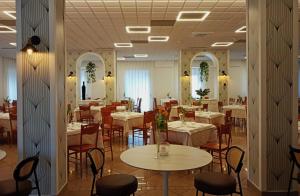restauracja z białymi stołami i krzesłami oraz stołami i krzesłami w obiekcie Hotel Colonne w mieście San Giovanni Rotondo