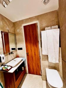 une salle de bain avec toilettes, lavabo et miroir dans l'établissement Mackenzie Luxury Boutique Stays, à Mussoorie